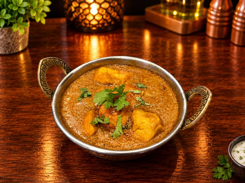Bhuna : curry épais aux épices et coriandre fraîche, servi dans un bol en cuivre