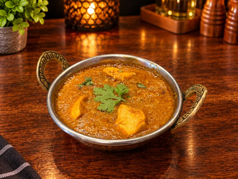 Curry : sauce aux épices et coriandre fraîche, servi dans un bol en cuivre