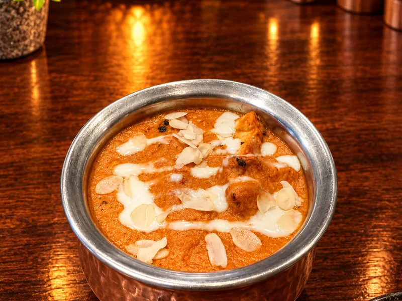 Poulet Butter : sauce onctueuse au beurre et aux amandes, servie dans un bol en cuivre