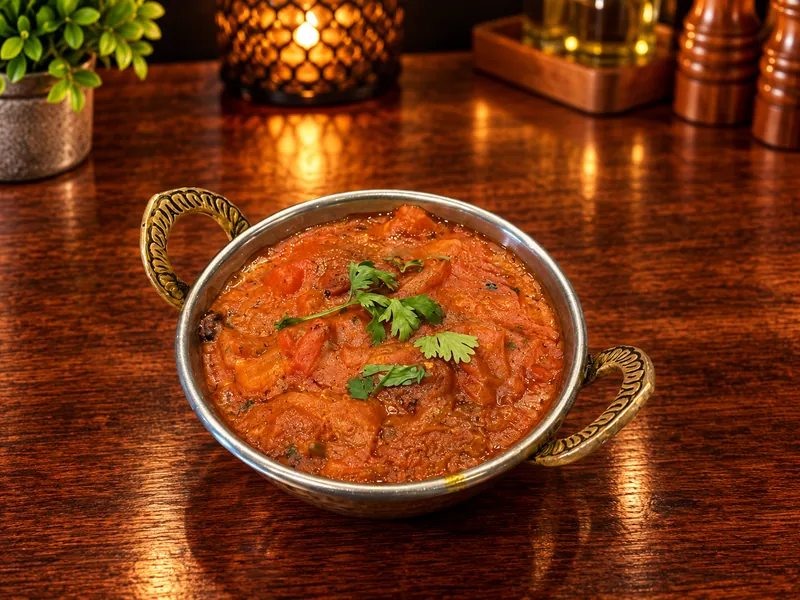 Rogan : curry à la tomate, servi dans un bol en cuivre
